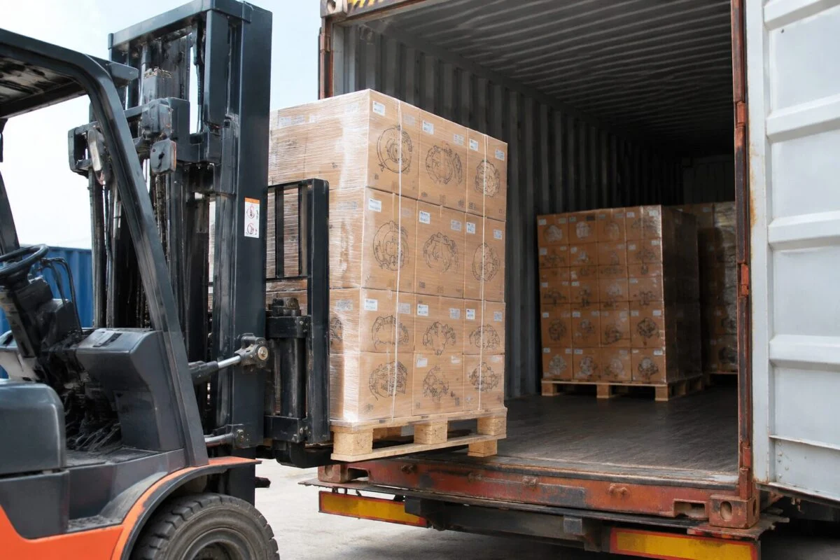 Palletized auto parts cartons being loaded into a shipping container